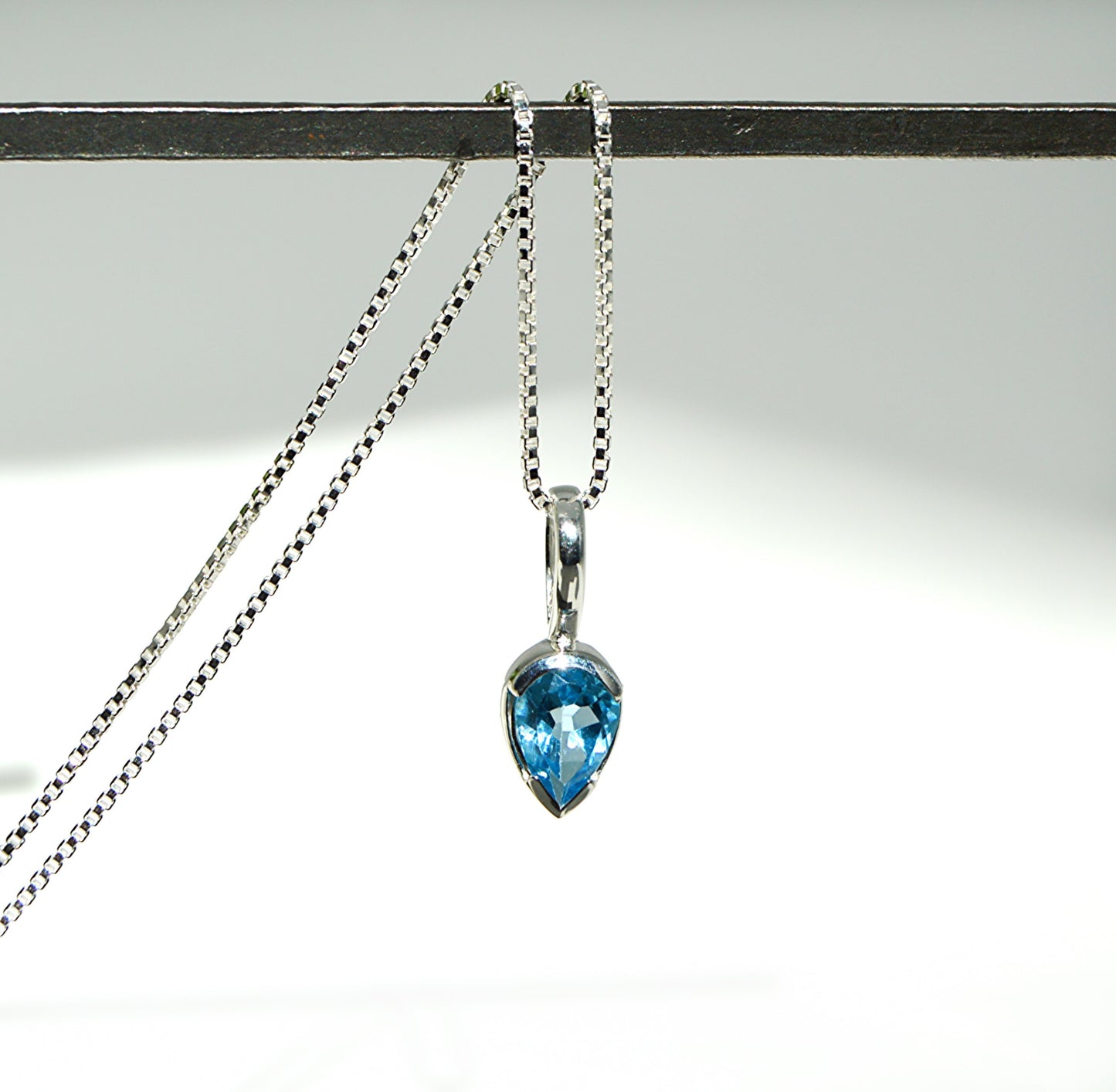 Necklace with a blue teardrop pendant on a white background
