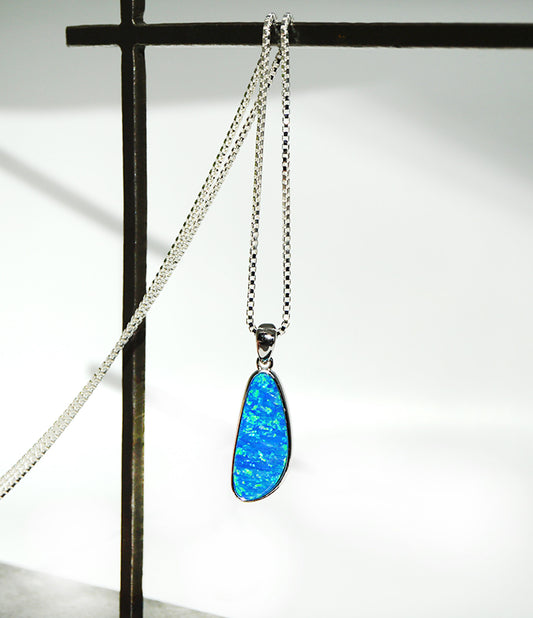 Blue opal pendant on a silver chain against a white background