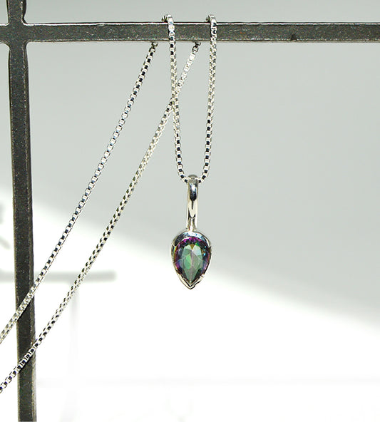 Teardrop-shaped pendant on a chain against a neutral background