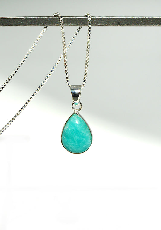 Turquoise teardrop pendant on a silver chain against a white background