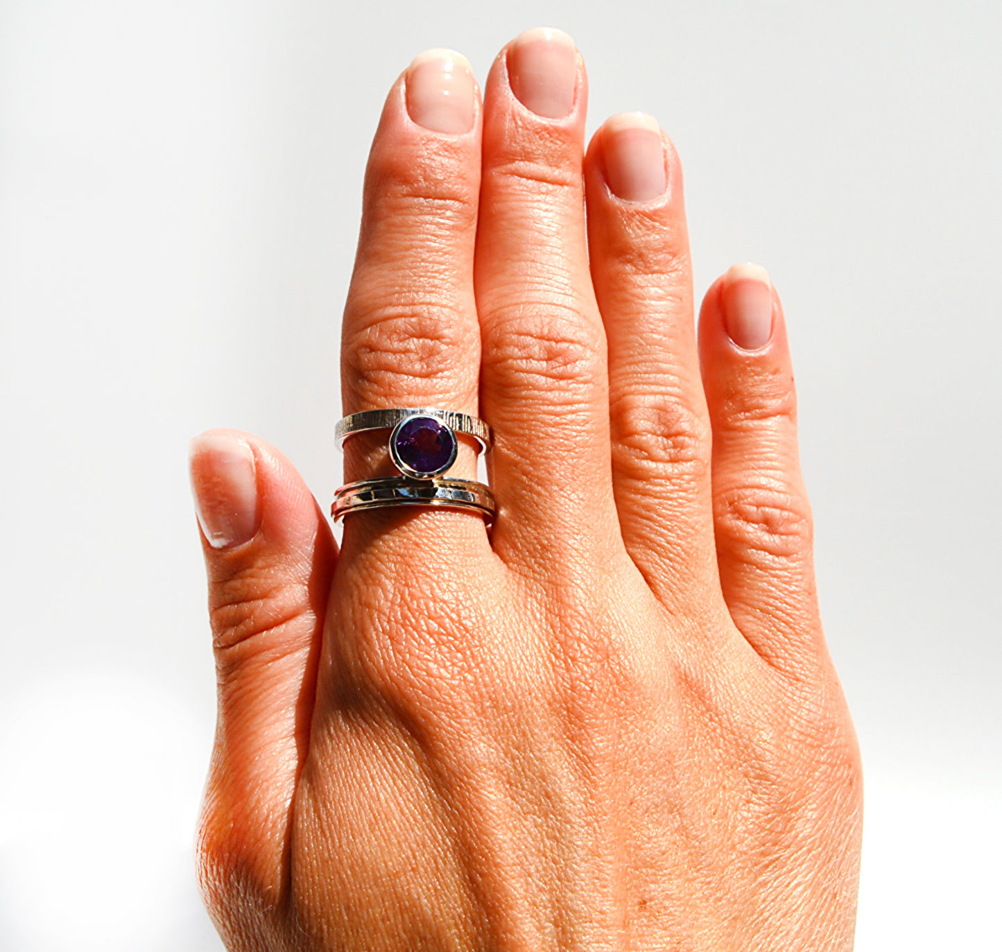 JeniMarie Jewelry with a statement ring featuring an amethyst stone and two bands one with a spinner ring. 