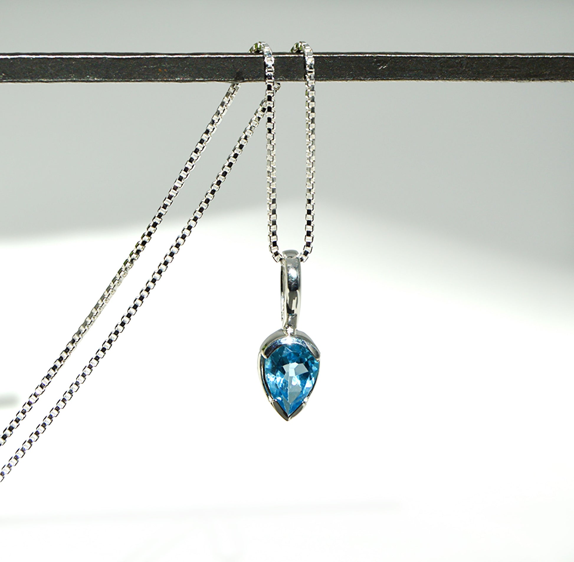 Necklace with a blue teardrop pendant on a white background