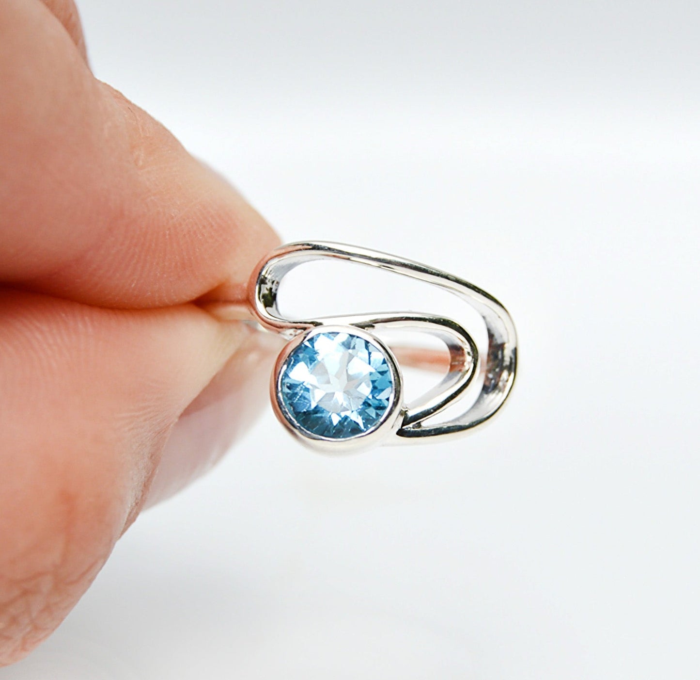 JeniMarie Jewelry with a statement blue topaz ring set in sterling silver showing a wave band design. 