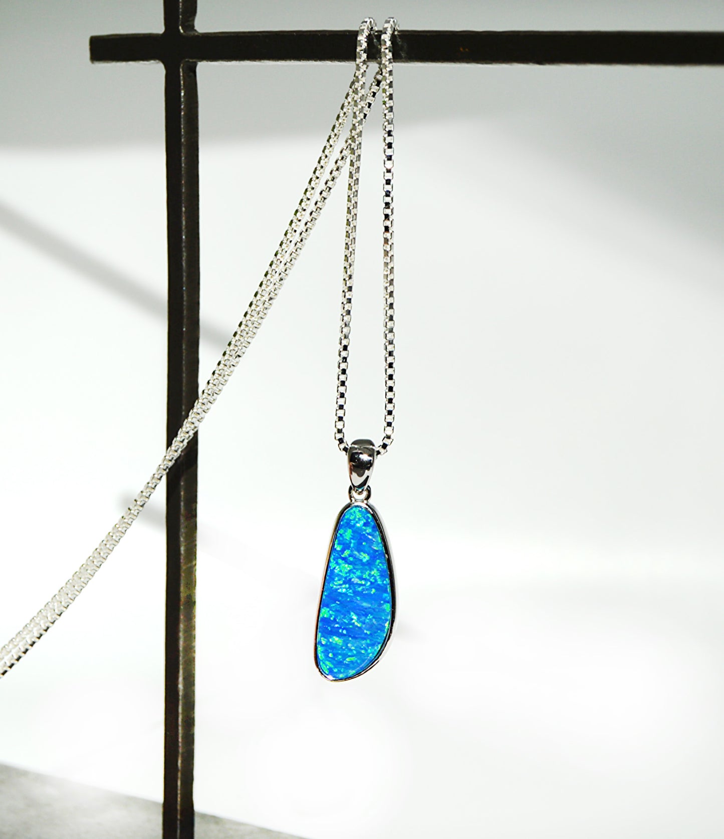 Blue opal pendant on a silver chain against a white background