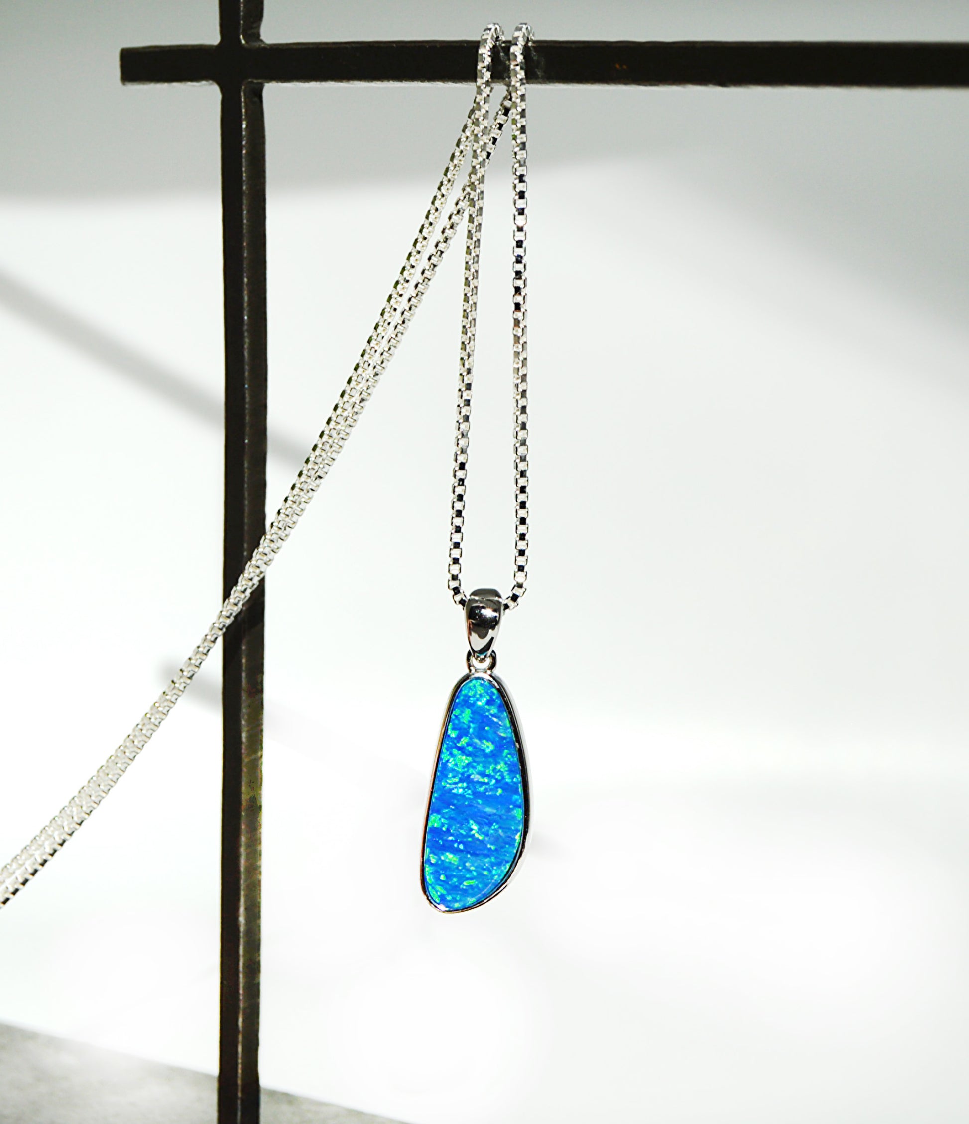 Blue opal pendant on a silver chain against a white background
