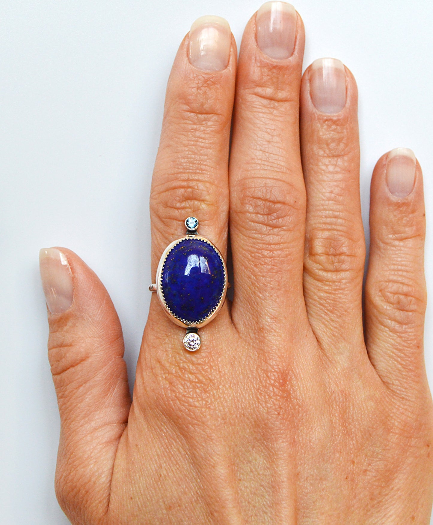 Lapis center stone handset in sterling silver with a london blue topaz accent stone. Size 9 