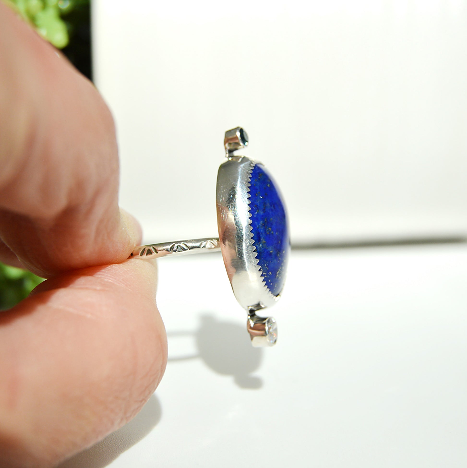 Lapis stone handset in a fine silver bezel with a textured design on the band the ring is offered in a size 9