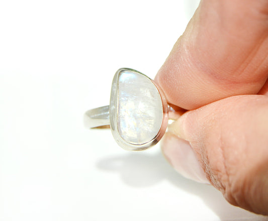 Silver ring with a large, oval moonstone gemstone held in a hand 
