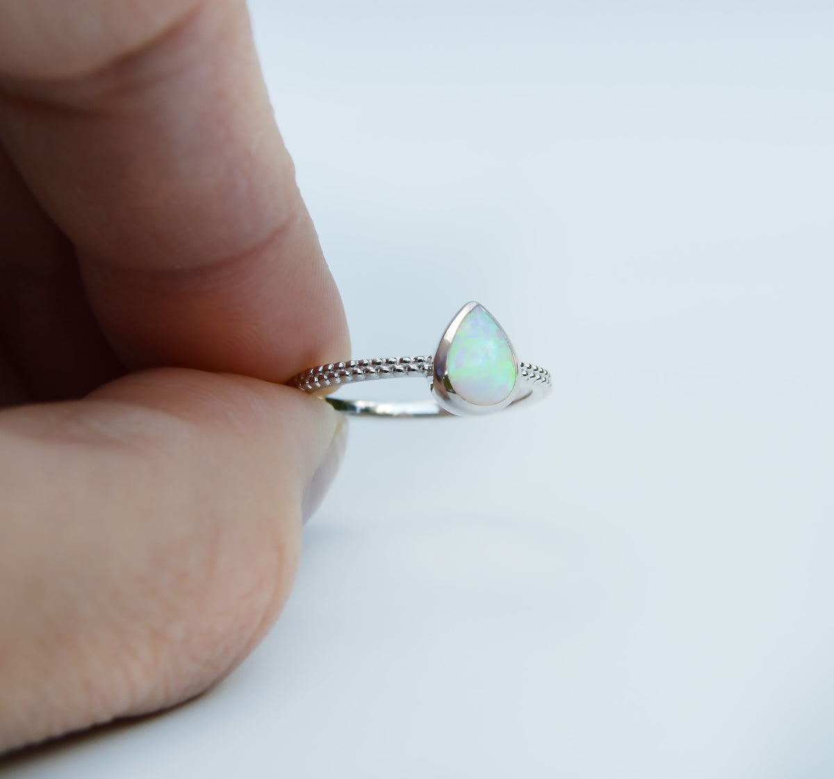 JeniMarie Jewelry with a beautiful tear drop shape opal set in polished sterling silver with a textured band making this an eye catching piece. 
