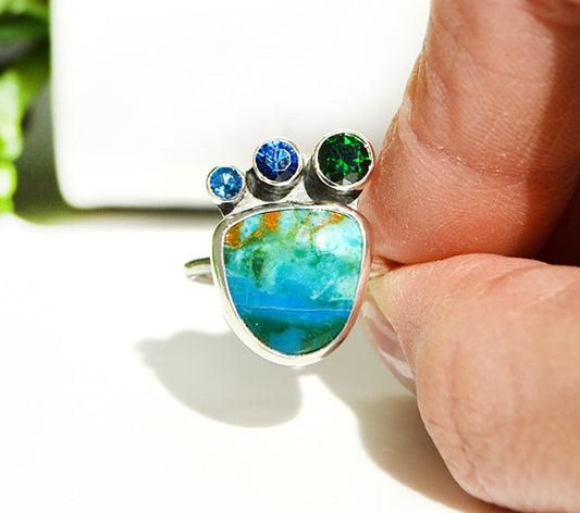 Peruvian Opal hand set in a fine silver bezel with accent stones on top with a sterling silver band. 