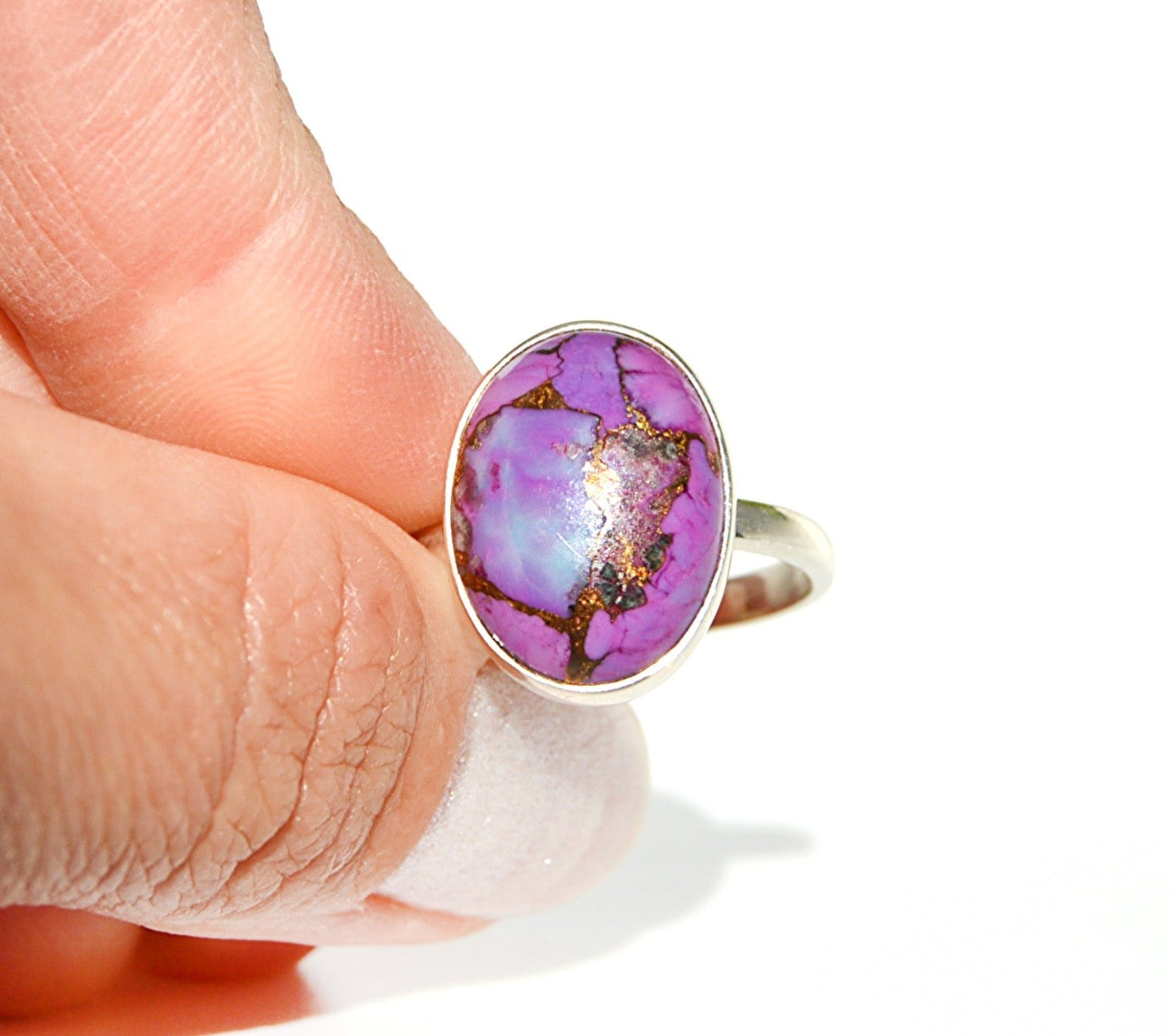 Hand wearing a ring with a purple turquoise gemstone 